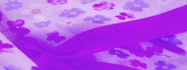 Küçük çiçek izleriyle süslenmiş hafif mor kumaşın bulanık görüntüsü yumuşak, zarif bir örtü ve şeffaf bir görünüm sunuyor. Kumaş dalgalı kıvrımlar halinde pürüzsüz akar..