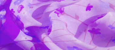 Küçük çiçek izleriyle süslenmiş hafif mor kumaşın bulanık görüntüsü yumuşak, zarif bir örtü ve şeffaf bir görünüm sunuyor. Kumaş dalgalı kıvrımlar halinde pürüzsüz akar..