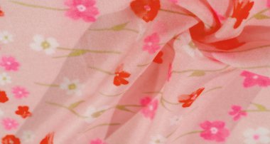 Yumuşak kıvrımlı pembe çiçekli kumaş ve kırmızı ve pembe renkli çiçek desenli bulanık görüntü. Kumaşın pürüzsüz dokusu ve narin kıvrımları yumuşak ve akışkan görünümünü arttırır..