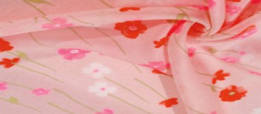 Yumuşak kıvrımlı pembe çiçekli kumaş ve kırmızı ve pembe renkli çiçek desenli bulanık görüntü. Kumaşın pürüzsüz dokusu ve narin kıvrımları yumuşak ve akışkan görünümünü arttırır..
