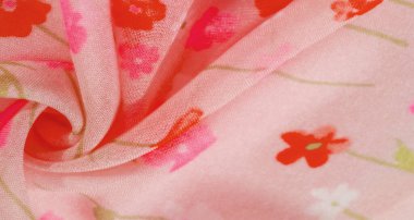 Yumuşak kıvrımlı pembe çiçekli kumaş ve kırmızı ve pembe renkli çiçek desenli bulanık görüntü. Kumaşın pürüzsüz dokusu ve narin kıvrımları yumuşak ve akışkan görünümünü arttırır..
