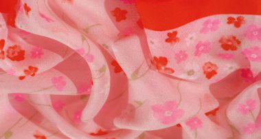 Pembe ve kırmızı tonlarda küçük çiçek desenleri içeren yumuşak, pembe kumaşın bulanık ayrıntıları, canlı kırmızı şeritlerle zarif bir şekilde akarak desene kontrastlık ve cazibe katıyor..