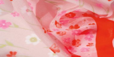 Kırmızı çiçek motifleri ve katı kırmızı aksanlarla süslenmiş akışkan pembe kumaşın bulanık görüntüsü. Yumuşak ve havadar malzeme canlı bir renk ve hassas bir doku kombinasyonu yaratır..