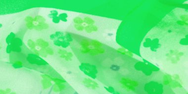 Açık yeşil tonlarda çiçek desenleri içeren esintili yeşil kumaş bulanıklığı. Kumaşın akışkan kumaşı dinamik bir hareket yaratıyor, canlı ve yumuşak dokuyu vurguluyor.