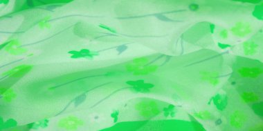 Soyut çiçek desenli, narin yeşil bir kumaşın bulanıklığı. Işık, akan kumaş yumuşak bir doku ve ince bir hareket yaratır. Zarif, doğadan esinlenilmiş estetik için mükemmeldir.