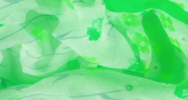 Yumuşak dalgalar ve dinamik kıvrımlar içeren küçük çiçek desenli yeşil bir kumaşın bulanıklığı. Hafif doku, doğadan esinlenilmiş tasarımlar için ideal olan kumaşın doğal ve taze görünümünü arttırır.