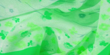 Küçük çiçek desenleriyle süslenmiş, akan yeşil bir kumaşın bulanıklığı. Hafif doku ve dinamik kıvrımlar doğadan esinlenilmiş bir görünüş için zarif ama enerjik bir estetik oluşturuyor.