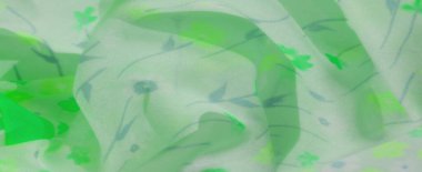 Canlı yeşil ve mavi renklerde basit, minimalist çiçek desenleriyle süslenmiş yeşil bir kumaşın bulanıklığı. Akan tasarım nazik kıvrımlar ve yaratıcı arka planlar için dingin bir estetik ideal yaratıyor..