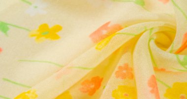 Dağınık pembe ve sarı çiçekli yumuşak sarı bir kumaşın bulanık görüntüsü. Çiçek deseni ve narin kıvrımlar, bahar ve yaz kıyafetleri için mükemmel bir hava akışı yaratıyor.