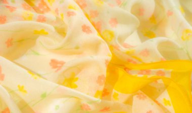 Canlı sarı kenarlar çiçekli kumaşı pembe, turuncu ve sarı çiçeklerle renklendiriyor. Yumuşak kıvrımlar ve havadar dokular tasarıma bir hafiflik ve hareket hissi verir..