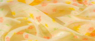 Yumuşak ve akışkan sarı çiçekli kumaş narin pembe ve turuncu çiçekler hafif, havadar bir doku oluşturur. Yumuşak kıvrımlar ve şeffaf kumaş durgun ve yaz hissi uyandırıyor..