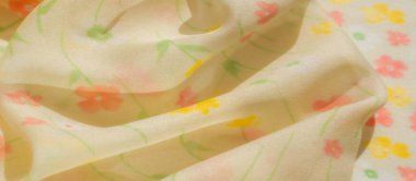 Yumuşak yeşilliklerle renklendirilmiş, pürüzsüz turuncu ve sarı çiçekli sarı kumaş bulanıklığı. Nazik kıvrımlar derinlik ve ince ışık yansımaları ekler..