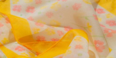 Beyaz, turuncu, sarı ve yeşil renklerinde pastel çiçek desenleriyle süslenmiş sarı kumaş bulanıklığı. Hassas kıvrımlar hareket ve doku ekler, kumaşların yumuşak ve havadar görünmesini sağlar..