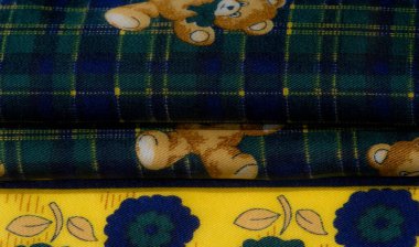 Sarı çiçekli kumaş ve yeşil ekose arka planda garip bir oyuncak ayı tasarımı içeren büyüleyici bir kumaş. Şablonların eğlenceli kombinasyonu canlı ve rahat bir tekstil yaratıyor..