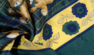 Yeşil ekose kumaş bulanıklığı ve etrafa saçılmış oyuncak ayılar. Sarı çiçekli kenar aksanları zıt bir element ekler ve çocuk tekstil ürünleri için eğlenceli ve canlı bir doku yaratır..