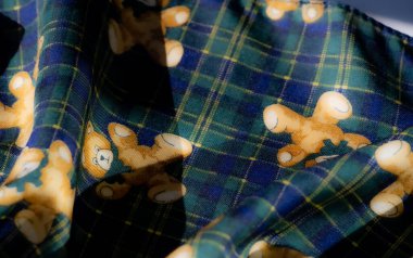 Sarı bir kenar boyunca ayıcık çizimleri ve çiçek aksanları olan rahat bir kumaşın bulanıklığı. Sıcak tonların ve neşeli tasarımların birleşimi nostalji hissi uyandırıyor.