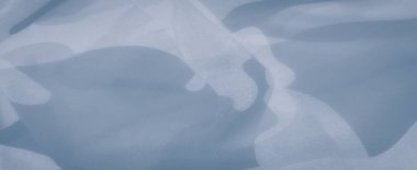 Üstüste binen desenli açık mavi kumaş bulanıklığı soyut şekiller yaratıyor. Yumuşak hareket ve narin kıvrımlar, gökyüzündeki yumuşak bulutları anımsatan sakin, akan bir atmosfer sunuyor..