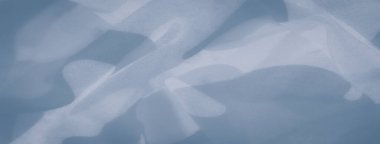 Açık mavi kumaş bulanıklığı çerçevede yavaşça dalgalanıyor, yumuşak dalgalar yaratıyor. İnce gradyanlar ve pürüzsüz dokular görüntüye narin hareketli, barışçıl, havadar bir estetik verir..