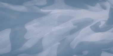 Yarı saydam mavi kumaş içinde soyut desenlerin bulanıklığı. Yumuşak ve havadar, kumaş nazikçe akar, ince ışık ve gölge oyunlarıyla ruhani ve dingin bir atmosfer yaratır..