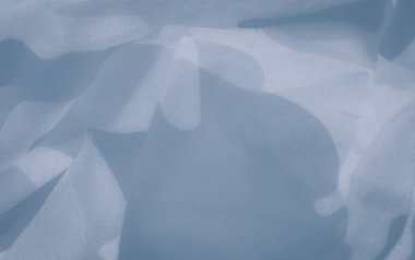 Açık mavi kumaş bulanıklığı çerçevede yavaşça dalgalanıyor, yumuşak dalgalar yaratıyor. İnce gradyanlar ve pürüzsüz dokular görüntüye narin hareketli, barışçıl, havadar bir estetik verir..