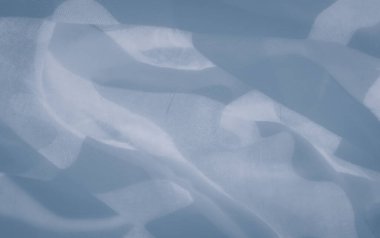 Yarı saydam mavi kumaş içinde soyut desenlerin bulanıklığı. Yumuşak ve havadar, kumaş nazikçe akar, ince ışık ve gölge oyunlarıyla ruhani ve dingin bir atmosfer yaratır..