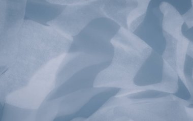 Açık mavi kumaş, yumuşak kıvrımlar ve dalgalar oluşturur. Yumuşak ve soyut bir desen yakalar. Havadar doku ve ince tonsal varyasyonlar dingin, dingin tasarımlar için mükemmel, ruhani bir atmosfer yaratıyor.