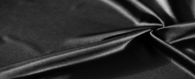 Yumuşak kıvrımlı siyah kumaş bulanıklığı, ışık ve gölgenin ince bir oyununda pürüzsüz ve parlak maddeler sergiliyor. Karmaşık doku ve derinlik soyut bir görüntü oluşturur..