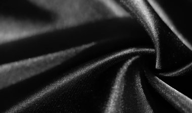 Yumuşak kıvrımlı siyah kumaş bulanıklığı, ışık ve gölgenin ince bir oyununda pürüzsüz ve parlak maddeler sergiliyor. Karmaşık doku ve derinlik soyut bir görüntü oluşturur..