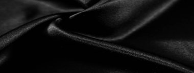 Pürüzsüz siyah kumaşlar ince kıvrımlarla kaplanmış. Yansıtıcı yüzey, ışık ve gölgelerin etkileşimini vurgular, lüks ve parlak bir son yaratır..