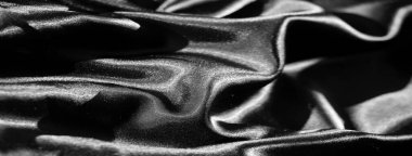 Bulanık parlak siyah kumaş zarifçe katlanır ve kıvrılır, hareket ve derinlik hissi yaratır. Lüks saten kumaş ışığı güzel yansıtıyor, zarif dokuyu ve zenginliği vurguluyor.