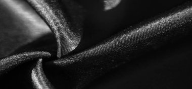 Zarif kıvrımlarla katlanmış pürüzsüz siyah kumaşın bulanık görüntüsü. Işık ve gölge oyunu parlak yüzeyi ve dokuyu vurgular, lüks ve akıcı bir görünüm yaratır..