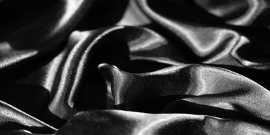 Yumuşak kıvrımlı ve parlak yansımalı siyah kumaş bulanıklığı pürüzsüz ve zarif bir doku yaratıyor. Işık ve gölgenin etkileşimi minimalist bir dizaynın lüks hissini arttırır..