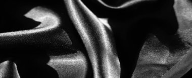 Yumuşak kıvrımlı ve parlak yansımalı siyah kumaş bulanıklığı pürüzsüz ve zarif bir doku yaratıyor. Işık ve gölgenin etkileşimi minimalist bir dizaynın lüks hissini arttırır..