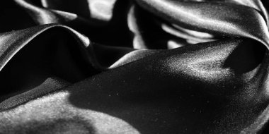 Yumuşak kıvrımlı ve parlak yansımalı siyah kumaş bulanıklığı pürüzsüz ve zarif bir doku yaratıyor. Işık ve gölgenin etkileşimi minimalist bir dizaynın lüks hissini arttırır..