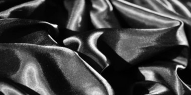 İnce kıvrımlı ve karmaşık kıvrımlı parlak siyah kumaş bulanıklığı. Röfleler ve pürüzsüz dokular, sofistike arka plan ve dokular için ideal bir zarafet ve lüks hissi getiriyor..