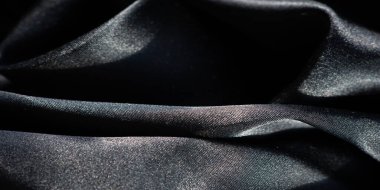 Yumuşak, parlak kıvrımları olan siyah bir kumaşın bulanıklığı, özenle gölgeleri ve gölgeleri yakalıyor. İnce dokular ve zarif kıvrımlar modern, minimalist bir estetik sağlar..