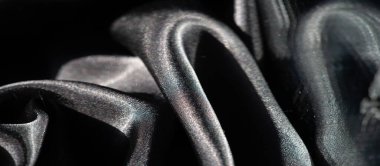 Dinamik kıvrımlı siyah kumaş bulanıklığı dokular ve gölgeler arasında soyut bir etkileşim yaratır. Yumuşak yansıtıcı yüzey, kumaşın kıvrımlarının sıvı hareketini vurgular..