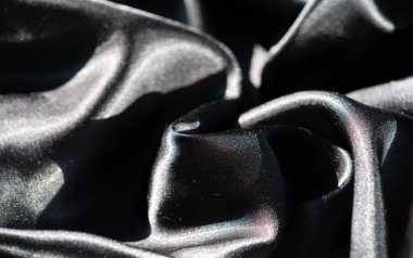 Dinamik kıvrımlı siyah kumaş bulanıklığı dokular ve gölgeler arasında soyut bir etkileşim yaratır. Yumuşak yansıtıcı yüzey, kumaşın kıvrımlarının sıvı hareketini vurgular..