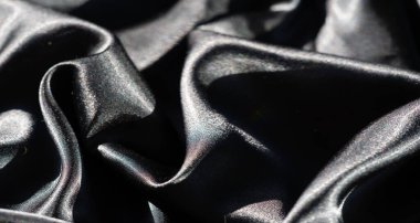 İnce çizgileri ve ince kıvrımlı deseni olan koyu bir kumaşın bulanıklığı soyut bir görüntü yaratıyor. Yumuşak doku ve pürüzsüz yansımalar genel tasarıma sanatsal bir element ekler..