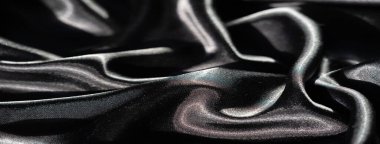 Soyut kıvrımlarda siyah saten kumaş bulanıklığı, keskin röfleler ve derin gölgeler, düz yüzeyi boyunca ışık ve karanlık arasında yüksek kontrastlı bir etkileşim yaratıyor..