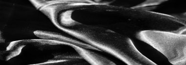 Keskin röfleleri ve zıt gölgeleri olan katlanmış siyah kumaşın bulanıklığı dinamik ve soyut bir görüntü yaratıyor. Pürüzsüz yüzey parlak bir efekt için ışığı yansıtır.