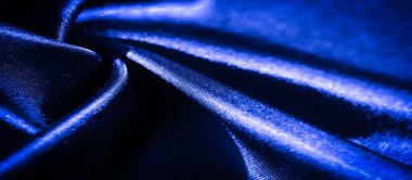 Karmaşık kıvrımları ve pürüzsüz dokuları olan parlak mavi bir kumaş. Görüntü, parıldayan kumaşın üzerindeki ışık ve gölge oyununu yakalar ve akıcılığını arttırır..