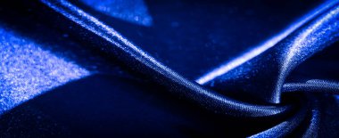 Mavi kumaştan bulanık, zarif bir şekilde bükülmüş, pürüzsüz ve yansıtıcı yüzeyini vurgulamak için ışığı ve gölgeyi yakalıyor. Katlar dinamik bir görsel doku yaratıyor, gelişmiş görünümünü geliştiriyor..