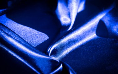 Yumuşak kıvrımlar ve kıvrımlarla zengin mavi kumaş bulanıklığı, maddenin ipeksi dokusunu vurguluyor. Işık oyunu kumaşın parlak yüzeyini güçlendirir, ona lüks ve dinamik bir görünüm verir.