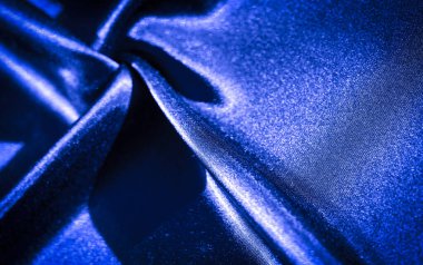 Belirgin kıvrımları ve kıvrımları olan parlak mavi kumaştan bir bulanıklık. Işığın ve gölgenin etkileşimi derinlik ekler, dokunun hem ipek hem de dinamik görünmesini sağlar..