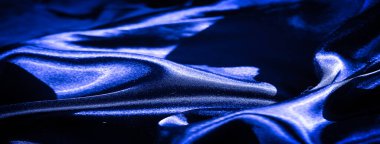 Pürüzsüz çizgileri olan parlak mavi kumaştan bir bulanıklık. Kumaşın parıltısı ışığı çok güzel yansıtıyor, lüks ve dinamik bir doku hissi yaratıyor..