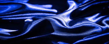 Yumuşak kıvrımları ve karmaşık dokusu olan ipeksi mavi kumaştan bir bulanıklık. Malzemedeki parlaklık, moda tasarımı için mükemmel olan zarafet ve lüks duygusunu arttırır..