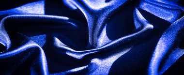 Derin mavi saten kumaştan bulanık, dalgalanan kıvrımlar halinde ustalıkla düzenlenmiş. İpeksi dokusu ve parlak mavi rengi ışıkla güçlendirilir. Kumaşa lüks ve sofistike bir his verir..