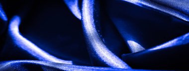 Derin mavi saten kumaş bulanıklığı soyut kıvrımlar ve yumuşak yansımalar yaratıyor, dengeli ışıklandırma altında zengin dokuyu ve pürüzsüz yüzeyi geliştiriyor.