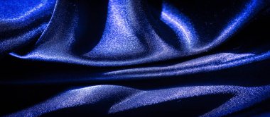 Saten benzeri, zengin, canlı mavi bir kumaş, zarif bir şekilde akan ve narin kıvrımlar oluşturan. Yumuşak ışığın altında parlayan ipek dokular sanatsal ve lüks bir görsel ekran oluşturuyor..